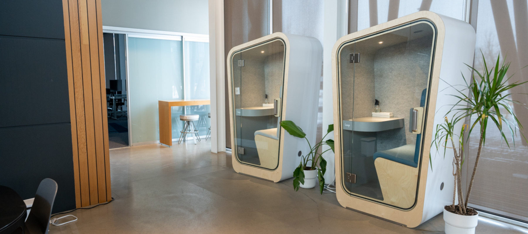two single loop phone booth style office pods against a wall