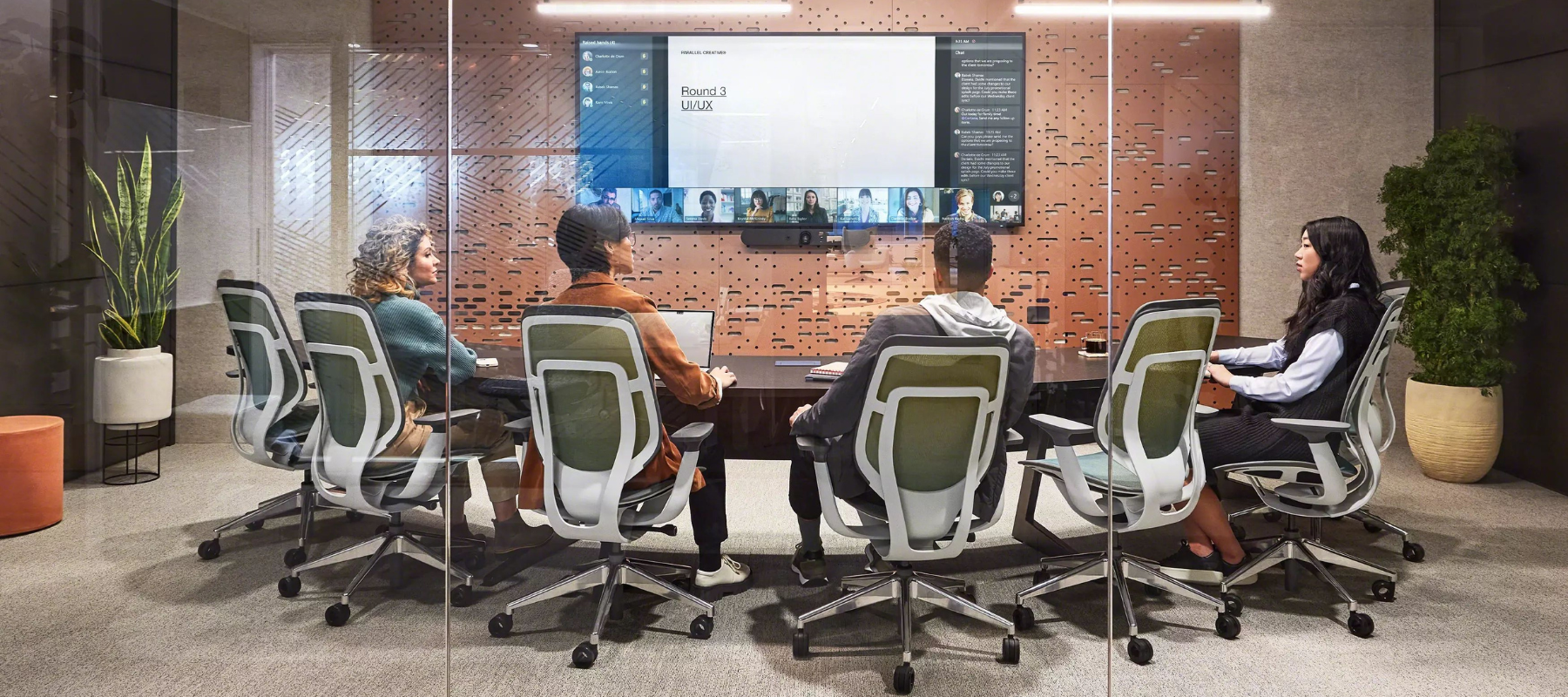 employees having a hybrid meeting sitting at a curved meeting table all facing the video conference