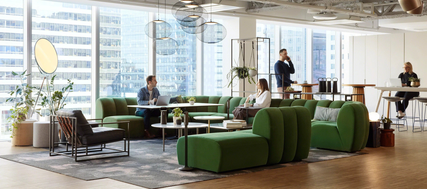 workplace with a social area featuring a green west elm couch, also with more focus spaces behind it